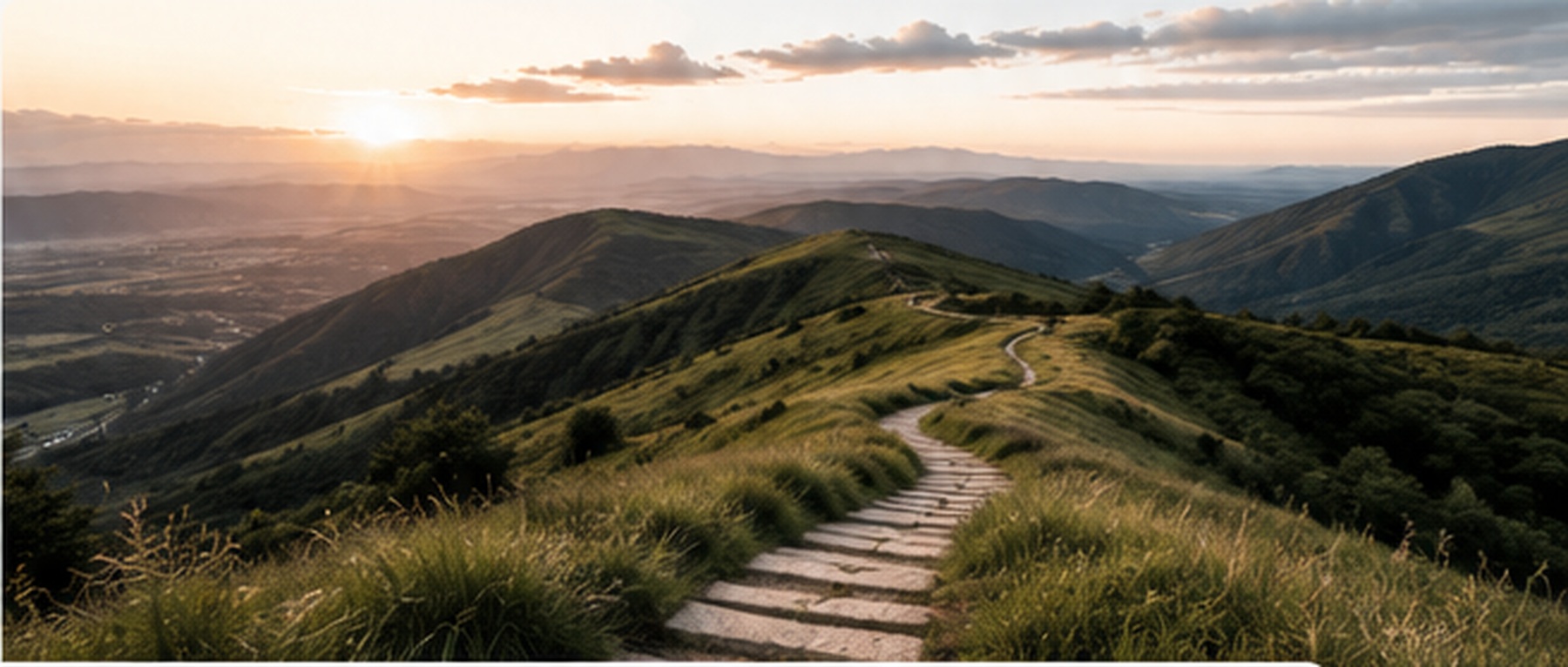 A winding path through a mountain landscape at sunrise.